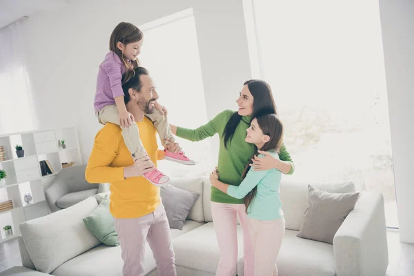 Amorosa gente de ensueño disfrutar pasar tiempo libre juntos mamá abrazo su pequeño preadolescente colegiala papá llevar piggyback adoptado más joven niño en casa sala de estar con sofá —  Fotos de Stock