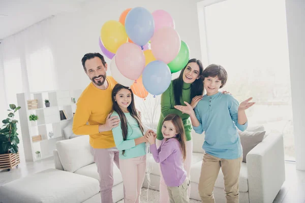 Pomysł na rocznicę kobiety rodziny. pięć osób tatuś mamusia cieszyć się wolny czas razem trzy małe nastolatki dzieci trzymać wiele balonów powietrza w domu pokój z kanapą — Zdjęcie stockowe