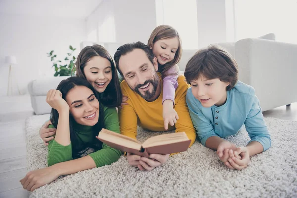 Zamknij się zdjęcie przytulne pozytywne ludzie rodzina tata tata czytać opowieść mama nastolatek dzieci słuchać mała dziewczyna punkt wskaźnik palec piggyback leżeć podłogi dywan w salonie dom — Zdjęcie stockowe