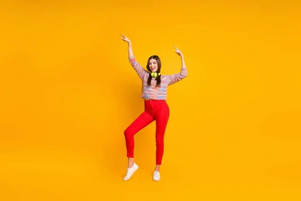 Foto de corpo inteiro de alegre menina positiva ouvir música música fone de ouvido dançarina de dança em festa de férias desgaste calças vermelhas calçado jumper isolado sobre fundo de cor brilhante — Fotografia de Stock