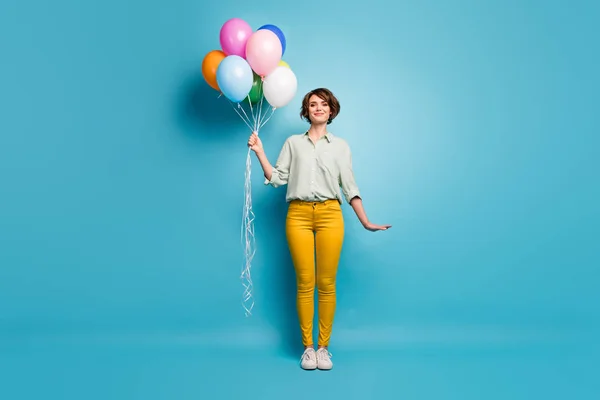 Lunghezza completa foto di attraente signora di buon umore è venuto a festa di compleanno portare molti palloncini d'aria colorati indossare casual camicia verde pantaloni gialli scarpe isolato colore blu sfondo — Foto Stock