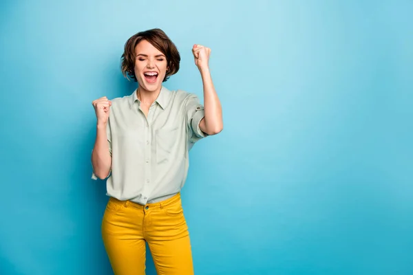 Ik ben rijk. Foto van vrij grappige dame verhogen vuisten schreeuwen luid vieren geld loterij winnende slijtage casual groen shirt gele broek geïsoleerde blauwe kleur achtergrond — Stockfoto