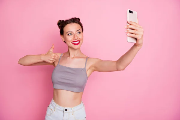 Pozitif neşeli gezgin kız portresi iyi yaz tatilleri cep telefonuyla selfie çekin başparmak işareti kullanın pembe arka planda izole edilmiş modern giysiler giyin. — Stok fotoğraf