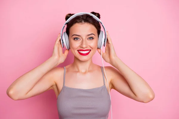 Porträt von charmanten schönen Gilr Musik hören mit ihren weißen Ohrhörern fühlen sich zufrieden tragen lässigen Stil Kleidung isoliert über rosa Hintergrund — Stockfoto