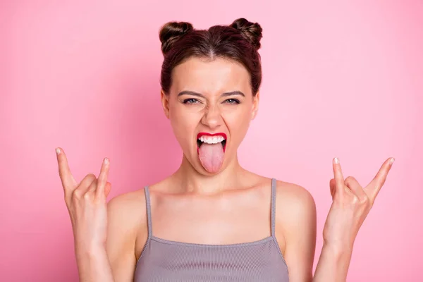 Foto van verbazingwekkende jonge dame grappige broodjes rode pomade tonen vinger hoorns steken tong uit mond gek rocker bij concert dragen casual grijs tank-top geïsoleerde roze kleur achtergrond — Stockfoto