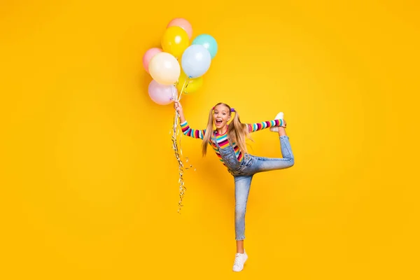 Full length photo of positive cheerful sport little girl hold many air balls she get after winning sport competition wear sweater sneakers isolated over bright shine color background — Stockfoto