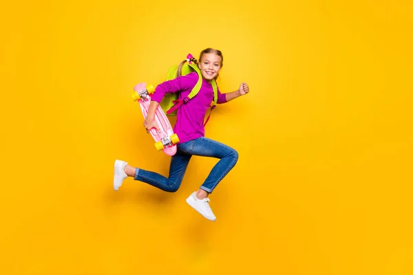 Full length body size view of her she nice attractive glad purposeful cheerful cheery girl jumping carrying longboard having fun isolated on bright vivid shine vibrant yellow color background — стоковое фото