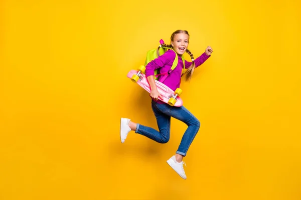 Full length body size view of her she nice attractive lovely glad cheerful cheery girl jumping carrying skateboard isolated over bright vivid shine vibrant yellow color background — стоковое фото