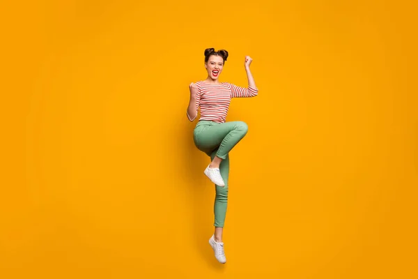 Foto de longitud completa de la señora viajera bastante atractiva saltando en alto levantar los puños gritar asombrado desgaste rayas rojo camisa blanca pantalones verdes zapatillas aisladas de color amarillo fondo —  Fotos de Stock