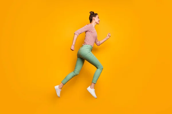 フルボディプロフィール写真の魅力的な可愛い女性ジャンプ高アップ急いで低価格ショッピング着用赤白プルオーバーシャツ緑のパンツ履物隔離された明るい黄色の背景 — ストック写真