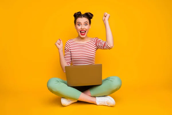 Wow Full size photo of pretty shocked lady sit floor hold notebook read good information raise fists wear striped red white shirt green pants shoes isolated yellow color background — Stock Photo, Image