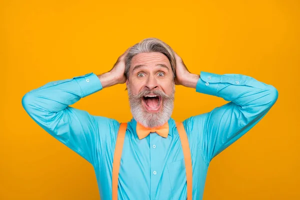 Closeup foto de roupas legais louco de cabelos brancos vovô boca aberta ver venda de compras anúncios braços na cabeça desgaste camisa azul suspensórios arco gravata isolado cor amarela fundo — Fotografia de Stock