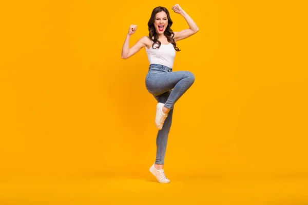 Full length photo of crazy cheerful lady good mood raise fists yelling loud support football team wear white tank-top jeans footwear isolated bright yellow color background — Stok fotoğraf