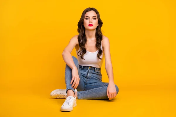 Foto de comprimento total de senhora engraçada sentar chão aconchegante não sorrindo beleza deslumbrante lábios vermelhos usam calça jeans tanque-top branco isolado cor amarela brilhante fundo — Fotografia de Stock