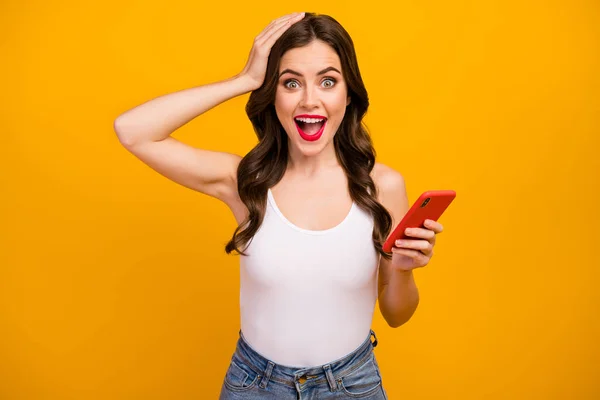 Photo of pretty funny lady hold telephone hands open mouth read cool comments youth blog followers wear white tank-top jeans isolated bright yellow color background — Stock Fotó