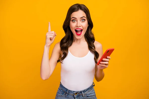 Photo of pretty lady hold telephone hands have creative new post idea raise finger up intelligent person open mouth wear white tank-top jeans isolated bright yellow color background — Stock fotografie