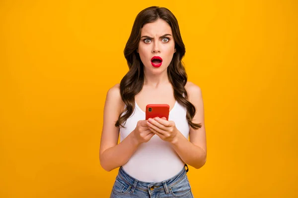 What Photo of pretty shocked lady speechless hold telephone hands open mouth read bad news wear white tank-top jeans isolated bright yellow color background — 图库照片