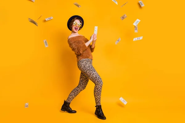 Full body photo of crazy lady hold bucks vzrušený nálada utrácet peníze štědrý člověk nosit měkký svetr leopard kalhoty čepice specifikace retro čepice boty izolované žlutá barva pozadí — Stock fotografie