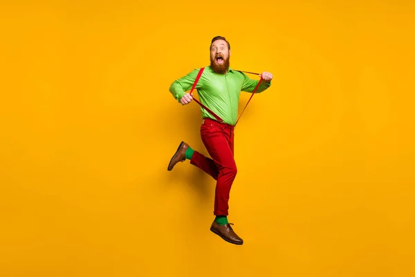 Full length photo of careless childish crazy funky man jump pull his modern suspenders scream feel rejoice wear stylish outfit shoes isolated over yellow color background — Stok fotoğraf