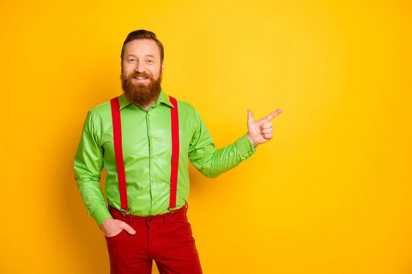 Photo of attractive funny guy indicate finger empty space presenting sale shopping opening wear green shirt red suspenders pants isolated shine color background — Stock fotografie