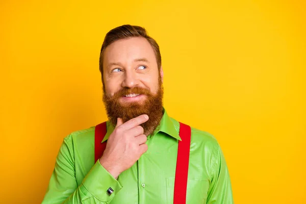 Closeup photo of funny red head guy look side empty space thinking about crazy trick arm on chin wear green shirt red suspenders isolated vibrant color background — Stock Photo, Image