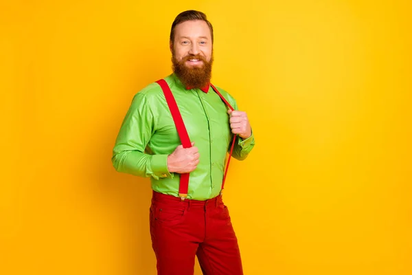 Foto di felice testa rossa ragazzo dentino sorridente elegante partito funky guardare tenere le mani bretelle indossare brillante camicia verde rosso papillon pantaloni isolato colore giallo sfondo — Foto Stock