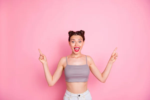 Photo of attractive lady cute buns red lips slim shapes indicate both arms empty space show low prices offer wear casual grey short top naked belly isolated pink color background — Stockfoto