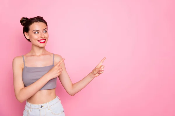 Photo of attractive lady cute buns red lips amazing shapes indicating fingers empty space show low prices wear casual grey short top naked belly isolated pink color background — ストック写真