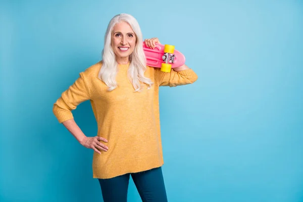 Portrait of her she nice-looking attractive lovely pretty charming modern cheerful cheery grey-haired woman carrying pink skate board isolated on bright vivid shine vibrant blue color background — Stock Fotó