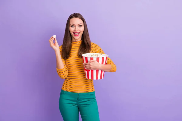 Portrait of enthusiastic girl have winter weekend holiday hold big striped pop corn box enjoy watching funny series wear good look lifestyle trendy jumper isolated over purple color background — Stockfoto