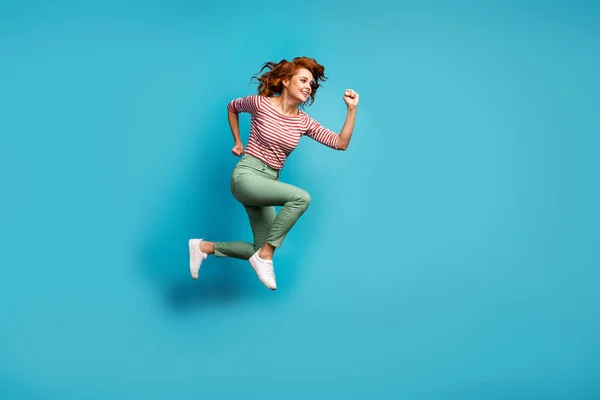 Foto de perfil de longitud completa de hermosa señora salto de alta carrera activa centro comercial de la temporada final desgaste casual rojo camisa blanca pantalones verdes calzado aislado azul color fondo —  Fotos de Stock