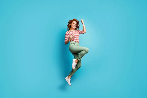 Goal. Full size profile photo of funny pretty lady jump high up raise fists winner sports competition wear casual red white shirt green trousers shoes isolated blue color background — Stockfoto