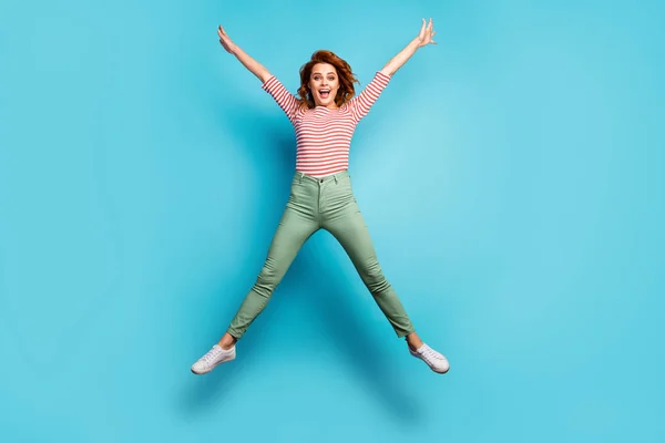 I am free. Full body photo of crazy lady jumping high rejoicing weekend sunny day spread hands wear casual red white shirt green trousers shoes isolated blue color background — Stockfoto