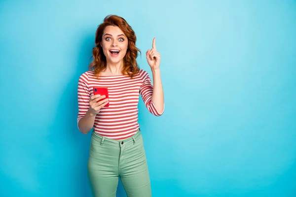 Portrait of excited crazy woman use cellphone type blog post think thoughts have incredible idea scream wow omg raise index finger up wear trendy jumper isolated over blue color background — Stockfoto