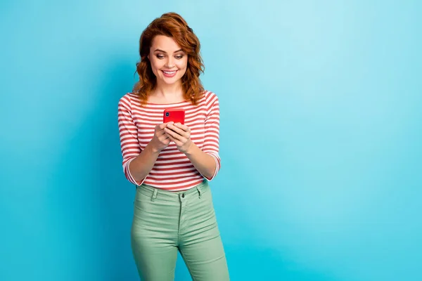 Retrato de mujer alegre positiva uso smartphone leer noticias de medios sociales ropa elegante jersey aislado sobre fondo de color azul — Foto de Stock