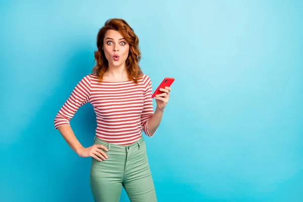 Portrait of astonished woman use smart phone get social media notification impressed scream wow omg wear good look sweater isolated over blue color background — 스톡 사진