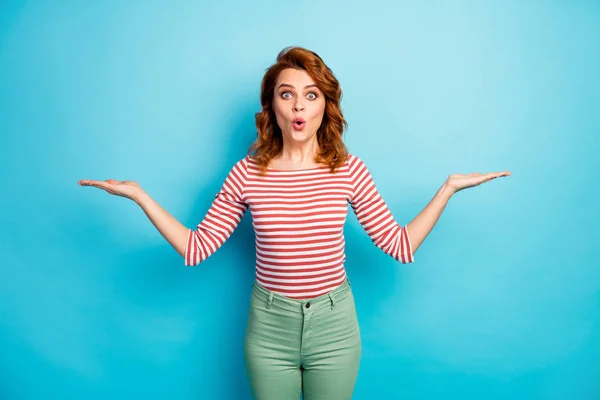 Portrait of astonished woman hold hand present unbelievable ads promo impressed scream wear casual style shirt isolated over blue color background — Stockfoto