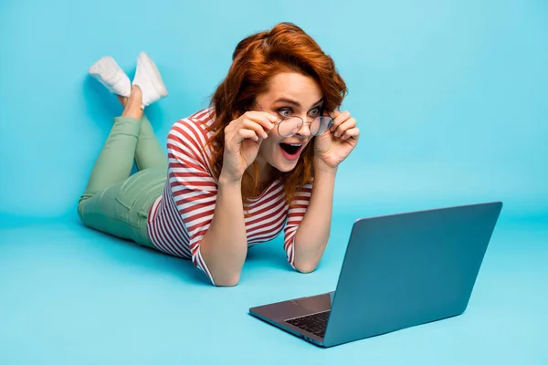 Full length close up photo impressed crazy woman lie floor use computer read incredible blogging notification scream wow omg wear white good look pullover isolated blue color background — Zdjęcie stockowe