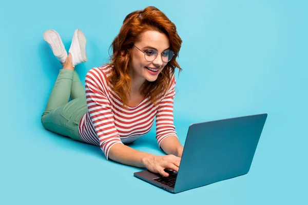 Full length close up photo positive woman lie floor work laptop have online conversation communication friends colleagues wear white gumshoes jumper isolated blue color background — Stockfoto