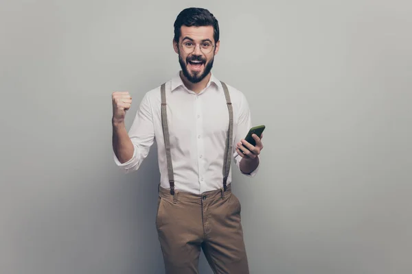 Delighted crazy boss company owner man use smartphone check his profit income finance win million dollars wear white shirt pants trousers suspenders brown isolated grey color background — 스톡 사진