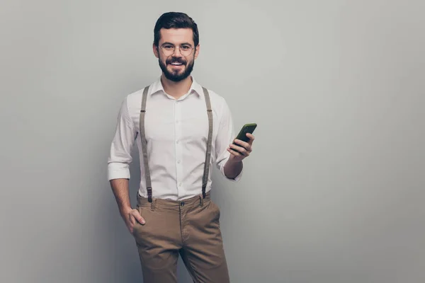 Портрет положительный успешный исполнительный работник использовать смартфон читать работы в социальной сети блоггер информации носить белые брюки изолированы на сером фоне цвета — стоковое фото