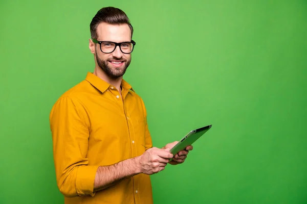 Профиль боковой вид портрет красивого привлекательного веселого парня в формальной рубашке, держа в руке цифровое устройство Wi-Fi быстрое соединение, изолированное на ярком ярком ярком зеленом фоне — стоковое фото