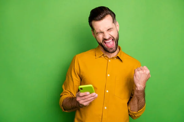 Portrait of his he nice attractive cheerful satisfied guy in formal shirt using cell celebrating lottery winning smm breakthrough isolated on bright vivid shine vibrant green color background — ストック写真