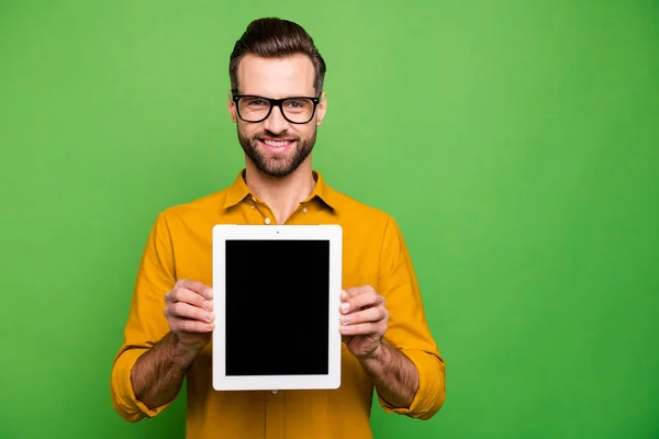 Portrait of nice attractive cheerful content guy in formal shirt holding in hands showing digital tablet new product isolated on bright vivid shine vibrant green color background Stock Photo