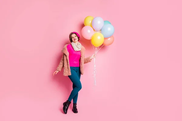 Foto de tamaño completo de viajero señora bastante divertida celebrar muchos globos de aire coloridos sorpresa para amigo usar abrigo de piel bufanda boina gorra pantalones zapatos aislados de color rosa fondo — Foto de Stock