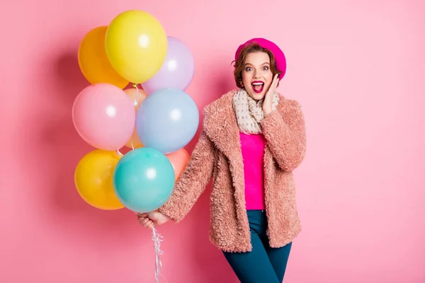 Foto von ziemlich funky Dame halten viele Luftballons aufgeregte Stimmung Hand am Kinn Geburtstag Überraschung tragen lässig stilvollen Pelzmantel Schal Baskenmütze Kleidung isoliert rosa Farbe Hintergrund — Stockfoto