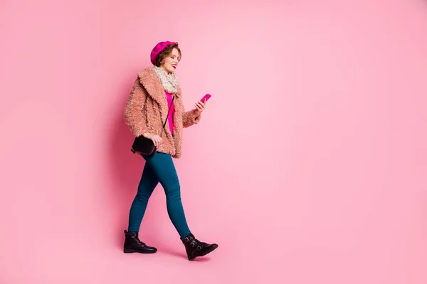 Full body profile side photo θετική χαρούμενη blogger κορίτσι πάει τα πόδια χρήση έξυπνο τηλέφωνο τύπου social media μήνυμα ειδήσεις φορούν διάστικτη πουλόβερ μπλε παντελόνι θιασώτες απομονωμένο ροζ χρώμα φόντο — Φωτογραφία Αρχείου