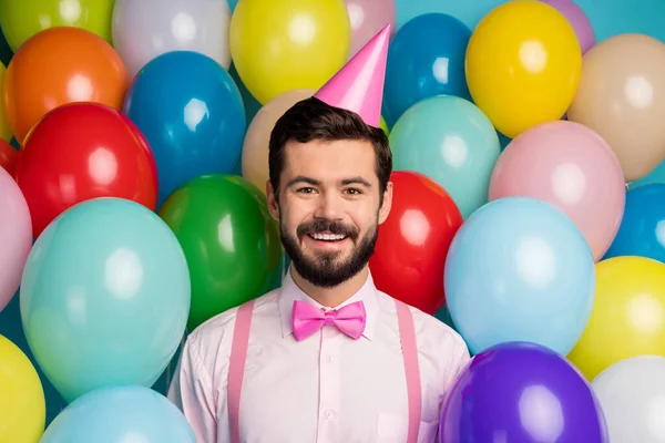 Foto von lustigen Gentleman Kerl umgeben bunte Luftballons Anordnung Geburtstagsparty tragen Papierkegelmütze rosa Hemd Fliege Strapse auf hell viele Luftballons Design Hintergrund — Stockfoto