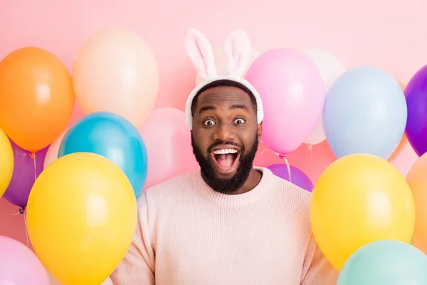 Photo of funny dark skin guy kolorowe dekoracje Wielkanoc party świąteczny nastrój otwarte usta nosić sweter puszysty króliczek uszy na balony różowy kolor tło — Zdjęcie stockowe