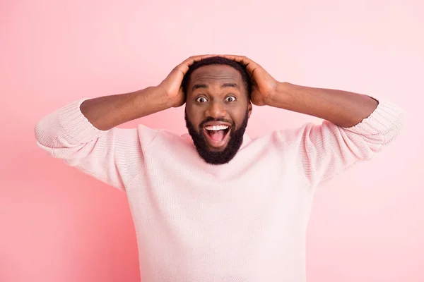 Photo of funny attractive dark skin young guy toothy beaming smiling listen good news open mouth arms on head wear warm knitted sweater isolated pink color background — Stock Photo, Image